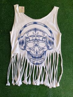 a tank top with a skull and headphones on the front is laying on green grass