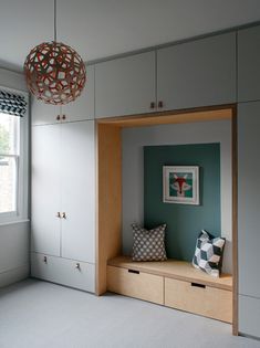 a room with white and blue walls, cabinets and a window in the corner that has a light fixture hanging above it