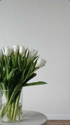 white tulips in a glass vase on a table