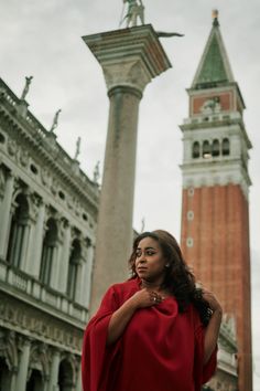 a woman standing in front of a tall clock tower