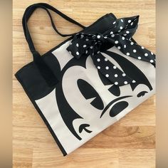 a black and white bag with polka dots on it sitting on a wooden floor next to a pair of scissors