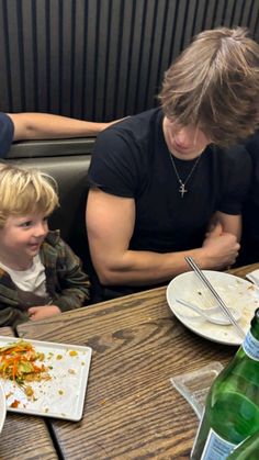 two children and an adult sitting at a table with plates of food in front of them