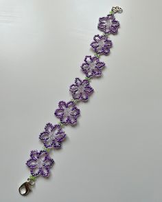 a purple bracelet with flowers on it and a pair of scissors hanging from the side