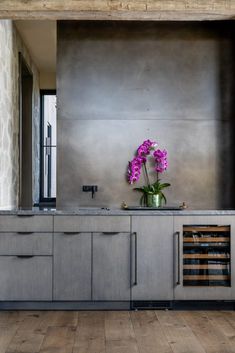 a vase filled with purple flowers sitting on top of a kitchen counter