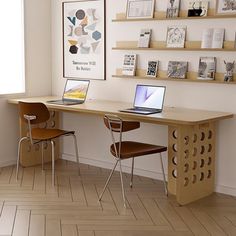 a desk with two laptops on top of it in front of a large window