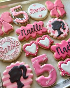 decorated cookies are arranged in the shape of letters and numbers on a cookie sheet with pink icing