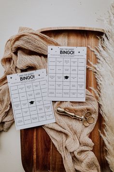 two sheets of paper on top of a wooden cutting board with scissors and yarn next to it