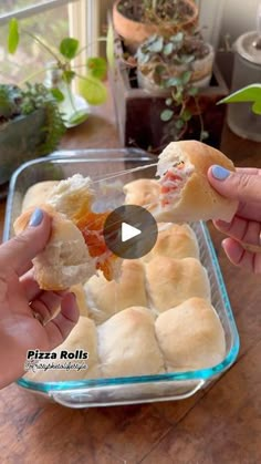 two hands holding small pieces of bread in front of a glass container filled with food