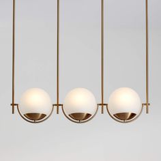 three white balls are hanging from a brass chandelier with four lights in the middle