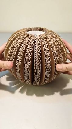 two hands holding an origami ball on top of a table