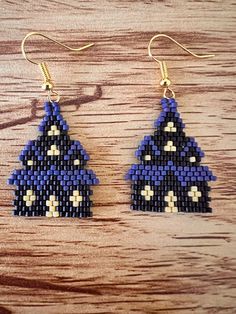 a pair of blue and white beaded earrings sitting on top of a wooden table