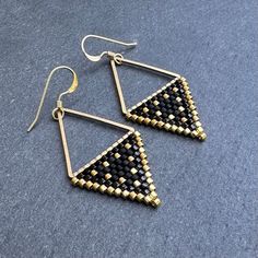 These beaded triangle shaped earrings are handwoven one bead at a time with Miyuki glass seed beads. A time intensive and intricate craft, each bead is carefully hand stitched in order to create an evenly woven beaded fabric. The process requires focus, patience and dedication, as even a small pair of beadwork earrings can take hours to complete. I love the contrast with the matte and shiny black beads... my favorite! Handwoven Brick Stitch Beadwork Miyuki delica glass seed beads in  Matte black Gold Triangle Earrings, Stitch Earrings, Beadwork Earrings, Beaded Fabric, Brick Stitch Earrings, Fabric Beads, Triangle Earrings, Seed Bead Earrings, Brick Stitch