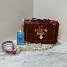 a small purse with a chain around it and a book on the front, sitting on a table