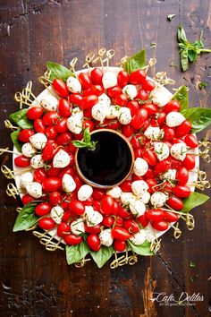 a platter filled with cherry tomatoes and mozzarella cheeses, garnished with basil leaves