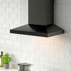 a black stove top oven sitting next to a pot on a kitchen counter with white tiles