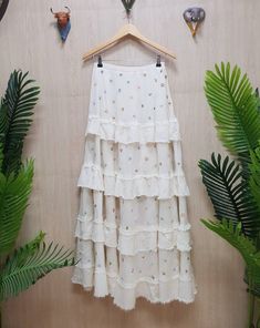 a white skirt hanging on a wall next to plants