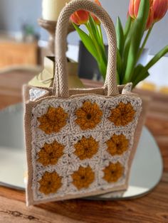 a crocheted bag with flowers in it sitting on a table