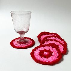 two crocheted coasters and a wine glass on a table