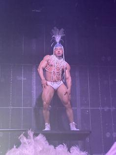 a man in a bodysuit standing on top of a shelf with feathers around his neck