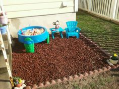 the backyard is filled with plastic toys and gravel, including two children's chairs