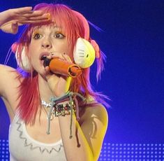 a woman with pink hair holding a microphone