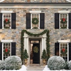 a large stone house with black shutters and wreaths