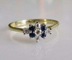 This is a vintage 9ct yellow gold flower cluster ring set with 5 diamonds and 4 blue sapphires. The flower cluster measures 9mm by 6mm and the band width is 2mm at the back. Fully hallmarked 375 (9ct gold), made in the year 1984 and weighs 1.6 grams. Size UK M 1/2 or  USA 6 1/4 Gold Flower Engagement Ring, Sapphire Ring Designs, Round Solitaire Ring, Flower Cluster Ring, Cute Promise Rings, Round Solitaire Rings, Gold Claddagh Ring, Amethyst Cocktail Ring, Cluster Ring Set