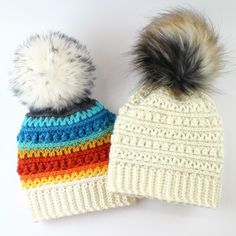 two knitted hats with pom - poms on them sitting next to each other