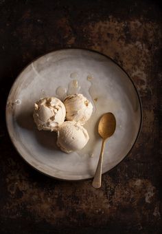 two scoops of ice cream on a plate with a spoon