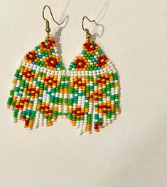 a pair of colorful beaded earrings on a white surface