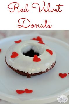 a white plate topped with a donut covered in frosting and red heart shapes