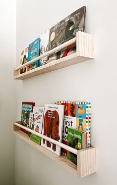 two wooden bookshelves with children's books on them in a white room