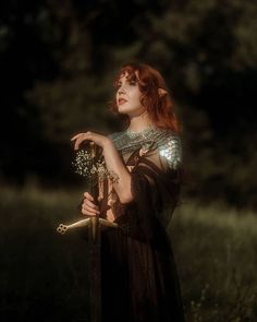 a woman with red hair is holding a flower in her hand and looking up at the sky