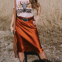 A jewel toned rust orange midi satin skirt. Features a high elastic waist silhouette, lightweight fabrication, a fluted slip shape, and a shimmering finish.  Perfect for western boho style lovers looking to add some vegas splash to their graphic tees and basics.  Fit: S 4-6 M 6-8  L 10-12 XL 12-14 Satin Skirt And Cowboy Boots, Flowy Satin Skirt For Fall, Relaxed Satin Skirt For Fall, Red Satin Skirt For Summer, Red Satin Bottoms For Summer, Red Satin Summer Bottoms, Fall Satin Long Skirt, Satin Long Skirt For Fall, Orange Flowy Skirt For Fall