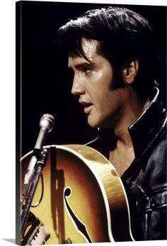 elvis presley singing into a microphone and holding an acoustic guitar in front of his face