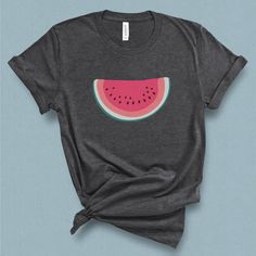 This minimal watermelon graphic t-shirt with its subtle retro feel comes straight from the pages of yesteryear. This wedge of watermelon graphic tee is supper sweet without being sticky. Its a perfect companion for your a pair of jean shorts and a hot summer day. DETAILS This Beautiful graphic t-shirt is made of 49% to 100% combed and ring-spun cotton and is very soft and comfortable to wear. Check the size card for specific fabrications per color. We use DTG technology and eco friendly inks all Cute Graphic Design Tops For Summer, Fun Summer Tops With Graphic Design, Summer Tri-blend Shirt With Graphic Print, Cute Summer Graphic T-shirt, Cute Summer T-shirt With Graphic Design, Pink Fruit Print T-shirt For Summer, Pink Graphic Design Shirt For Summer, Green Graphic Tee With Fruit Print, Pink Fruit Print Graphic Tee