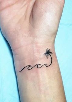 a small palm tree tattoo on the left wrist and an ocean wave in the middle