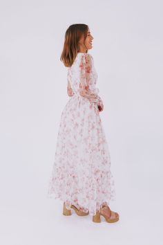 Get ready to turn heads with the Romance In The Air Dress! This off-white dress boasts a stunning floral print and a flattering V neckline. The smocking around the waist and sleeve cuffs creates a perfect fit, while the long sheer sleeves add an elegant touch. With a maxi length and a tier on the skirt, this dress is sure to make you feel like a romantic dream! Details Off white dress with floral print V neckline Smocking around waist and sleeve cuffs Fully lined Long, sheer sleeves Maxi length Feminine Midi Dress With Smocked Cuffs For Brunch, White Floral Dress With Smocked Bodice, White Feminine Floral Dress With Smocked Bodice, Midi Dress With Smocked Cuffs For Garden Party, Feminine Summer Dress With Smocked Cuffs, Elegant White Midi Dress With Ditsy Floral Print, Feminine Floral Dress For Daywear, Spring Floral Maxi Dress With Smocked Bodice, White Modest Maxi Dress For Brunch