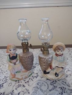 three small glass vases sitting on top of a doily covered table with lace