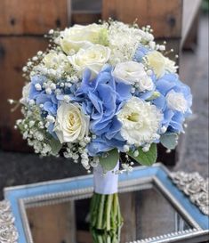 a bouquet of white and blue flowers sitting on top of a table next to a mirror