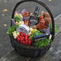 a wicker basket filled with different types of food and drinks sitting on top of a wooden bench