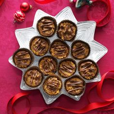 there are many cupcakes on the plate with red ribbons around them and decorations