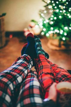 someone is taking a selfie in front of a christmas tree with their feet on the ground