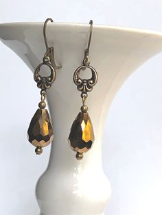 Antique bronze earrings feature brass Fleur de Lis connectors with vintage bronze fire polished faceted glass drops. Antique brass lever back earwires complete these brass Fleur de Lis earrings and they would be ideal for gift giving or anniversary gift, gift for mom, gift for girlfriend, or special occasion jewelry. We are proud to be part of the sustainable fashion movement by repurposing jewelry and components which would otherwise be discarded. We believe our company is responsibly reducing Gold Faceted Crystal Earrings For Gift, Elegant Copper Teardrop Earrings Gift, Elegant Faceted Brass Earrings, Antique Copper Earrings In Antique Gold, Bronze Metal Teardrop Earrings For Gift, Vintage Bronze Teardrop Earrings, Nickel-free Victorian Gold Earrings, Vintage Copper Teardrop Earrings, Gold Faceted Brass Earrings