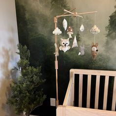 a baby's crib in front of a forest scene painted on the wall