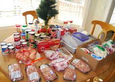 the table is full of food and drinks on it, along with some christmas tree in the background