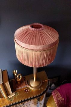 a pink lamp sitting on top of a dresser next to a mirror and other items