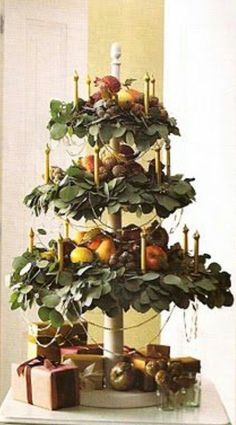 a christmas tree made out of candles and fruit on top of a table with presents