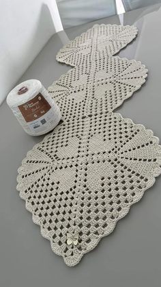 a crocheted doily with a roll of yarn next to it on a table