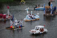 several boats float down the river with floats on them and people in white suits standing on rafts